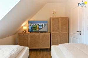 a room with two beds and a tv on a dresser at Haus Christine Ferienwohnung 4 in Langeoog