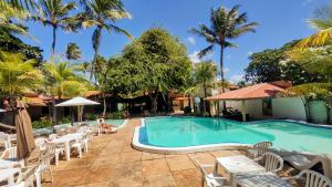 a swimming pool with white chairs and a resort at Pousada do Sol in Aquiraz