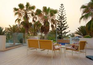 a patio with a table and chairs and palm trees at Villa Sable de Mirleft Luxury Apartment in Mirleft