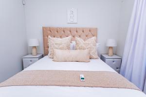 a bedroom with a large white bed with two night stands at Gaborone City Center stay, ultrafast wifi & near CBD & Airport in Joverega