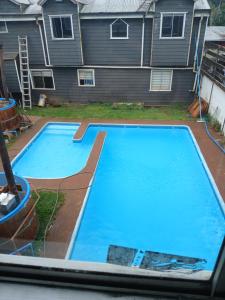 a large blue swimming pool in front of a house at Cabaña con tinaja de hidromasaje in Valdivia