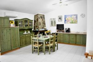 a kitchen with green cabinets and a table with chairs at Villa giulia in Domus de Maria