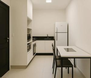a white kitchen with a table and a refrigerator at Condomínio Diamond - Novo - Centro in Corumbá