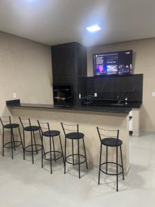 a bar with stools in a room with a tv at Condomínio Diamond - Novo - Centro in Corumbá +1 photo