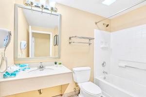 a bathroom with a sink and a toilet and a mirror at Studio with Hot Tub & Pool Near Universal Studios in Orlando