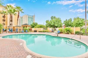 a large swimming pool with blue chairs and trees at Studio with Hot Tub & Pool Near Universal Studios in Orlando +9 photos
