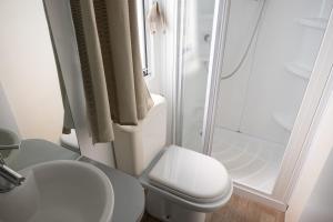 a white bathroom with a toilet and a shower at Redabba House in Arzana