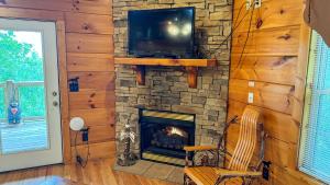 a living room with a fireplace and a tv on a stone wall at A Painted Pony in Sevierville