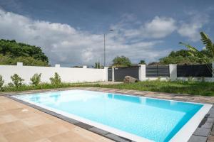 una piscina en un patio trasero con una valla blanca en Villa Kassav, en Port-Louis