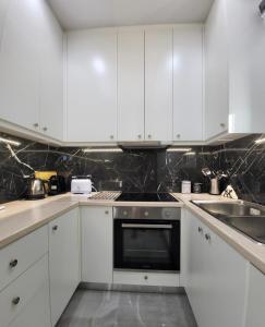 a kitchen with white cabinets and a black oven at Luxury apartment center of Varkiza Resort in Vari