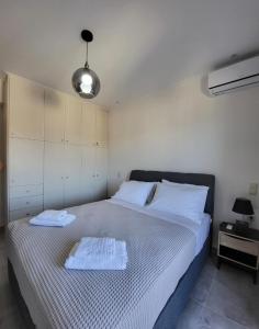 a bedroom with a bed with two towels on it at Luxury apartment center of Varkiza Resort in Vari