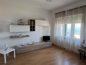 a white living room with a television and a window at Appartamento Morelli Beach - Via Giacomelli 55 in Follonica
