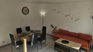 a living room with a table and a red couch at Maison hortensia in Le Cheylard