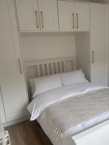 a white bed with white cabinets in a bedroom at Quarry Cottage in Dublin