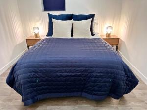 a bed with a blue comforter and two night stands at Chic & Modern 2BR Apartment - Luxury Manchester Retreat in Manchester