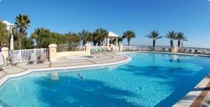 a large blue swimming pool with palm trees and the ocean at Le Reve Chamant- Martinique Villa in Gulf Highlands
