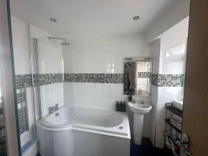 a white bathroom with a tub and a sink at Cute and Comfy Apartment in Saint Helier Jersey