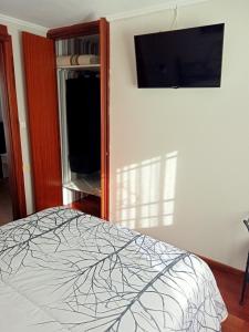 Un dormitorio con una cama y un televisor en la pared. en el apartamento de zocas, en O Barqueiro