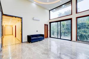 a living room with a couch and large windows at Hotel O DEVOM INN in Greater Noida