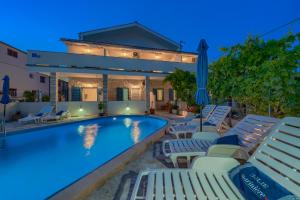 a swimming pool with lounge chairs and a house at VILA SENTIO MARE-Apartments Livaić Željko in Pirovac
