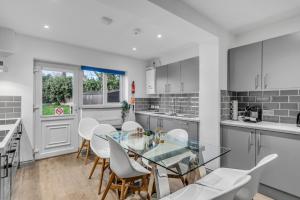 a kitchen with a glass table and white chairs at 7 Bed House Pitchford Road in Earlham