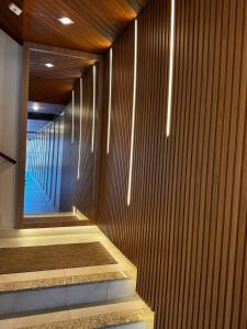 a bathroom with a wooden wall and a mirror at Apartamento Mar grosso 100 metros do MAR in Laguna +26 photos