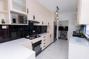 a white kitchen with white cabinets and a stove at Gaborone City Center stay, ultrafast wifi & near CBD & Airport in Joverega