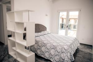 a white bedroom with a bed and a book shelf at La Dimora dell'Aquila in Castelnuovo del Garda