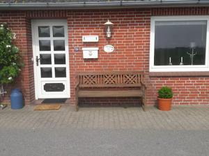eine Holzbank vor einem Backsteingebäude in der Unterkunft Ferienwohnung Schmettau in Nordstrand