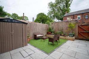 a small garden with chairs and a fence at Daisy Guest House in Oldham