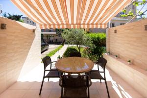 un patio con mesa y sillas bajo toldo en KlubNika, en Budva