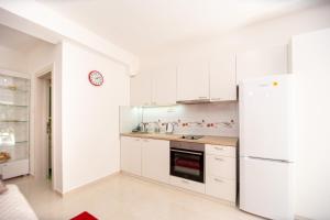 Una cocina con gabinetes blancos y un refrigerador. en KlubNika, en Budva