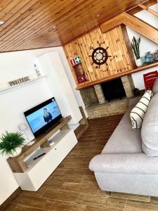 Una sala de estar con un sofá y un televisor. en La Villetta, en Torvaianica