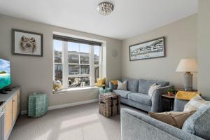 a living room with a couch and a tv at La Petite Maison Apartments in Brixham