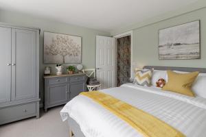 a bedroom with a large white bed with a yellow blanket at La Petite Maison Apartments in Brixham