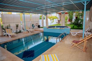 a swimming pool with chairs and a table and a swimming pool at Tranquil Villa, private Pool, Garden, Wifi, Fayoum in Qaryat at Ta‘mīr as Siyāḩīyah