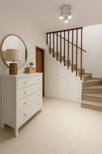 a room with a dresser and a mirror and stairs at Mala Kuća in Hodilje