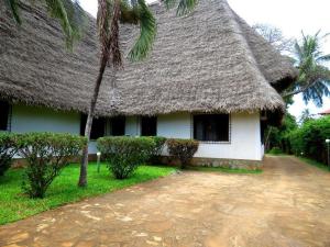 una casa con techo de paja y una palmera en Villa con baobab e piscina, en Malindi