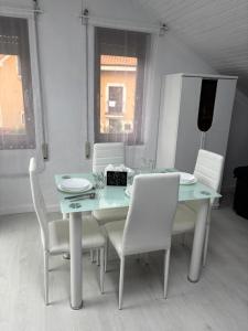 un tavolo da pranzo con sedie bianche e un tavolo e sedie blu di Apartamentos Redondo a Suances