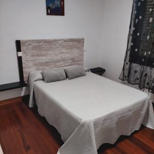 una camera da letto con un letto con copriletto bianco di Apartamentos Redondo a Suances Altre 2 foto