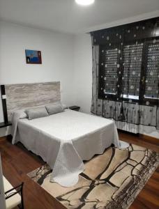 una camera con un letto con un tappeto e una finestra di Apartamentos Redondo a Suances