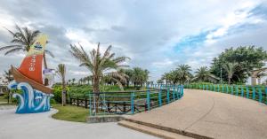 a curved walkway with a surfboard sign and palm trees at Duo Romance Hotel in Hualien City