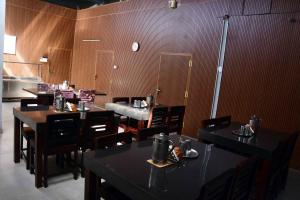 a restaurant with tables and chairs and a clock on the wall at Vanam Holidays in Ooty