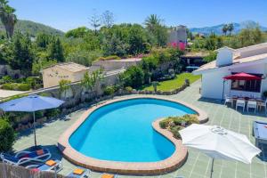 a swimming pool with umbrellas and chairs and a house at Villa Maite by Villa Plus in El Port