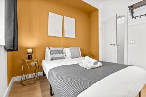 a bedroom with a large white bed with orange walls at Heart of the City Centre - Serviced Apartments in Manchester