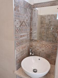 a bathroom with a white sink and a tile wall at Residenza Rivellini Tropea in Tropea +34 photos