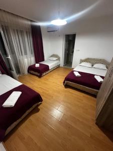 a hotel room with three beds and a wooden floor at Sara s Apartments in Ulcinj