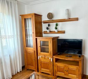 a living room with a tv and a wooden entertainment center at La Mermellina, 20 in Arriondas