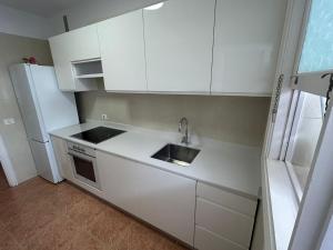 a kitchen with white cabinets and a sink and a refrigerator at CASA ROBERTO CANDELARIA,PARKING,AIR,WIFi in Candelaria