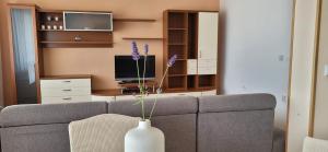 ein Wohnzimmer mit einem Sofa und einer Vase mit lila Blumen in der Unterkunft ALIANA apartment in Sečovlje